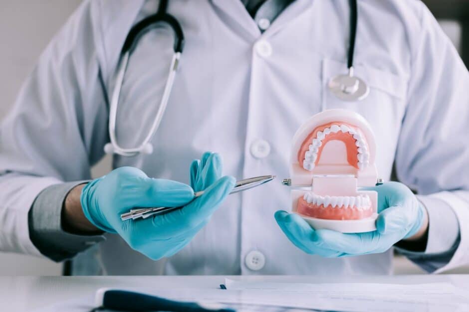 The dentist holds the pen and pointing to the denture.